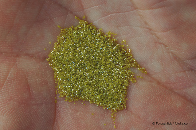 Kleine Ansammlung von gelb-gold farbenen Industriediamanten in der Mitte einer menschlichen Hand