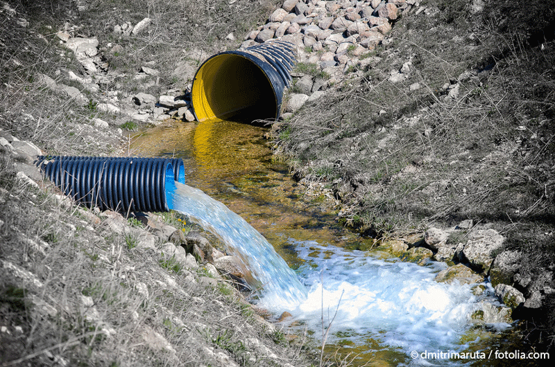 Außenaufnahme von zwei Abwasserrohren, aus denen Wasser in einen kleinen Bach geleitet wird