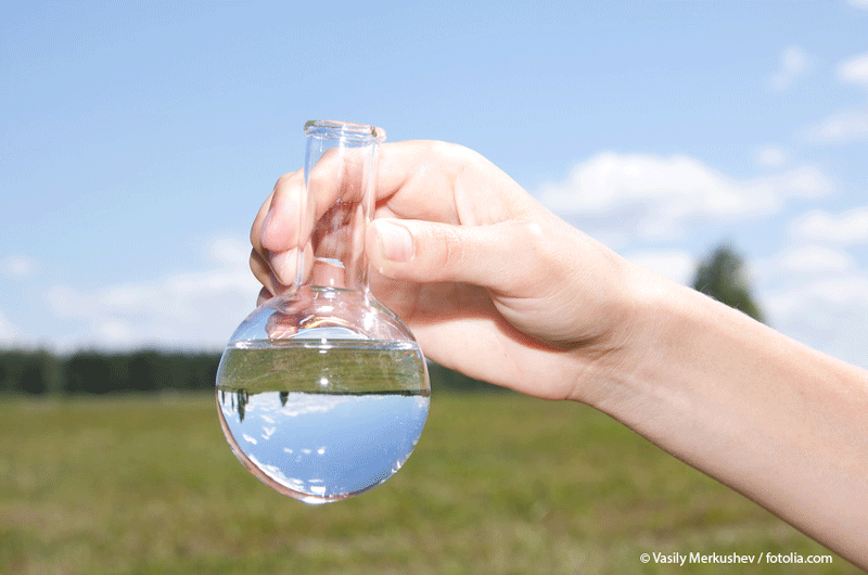 Nahaufnahme eines mit Wasser gefüllten Rundkolbens als Beispiel für die Probennahme aus dem Umweltkompartiment Wasser